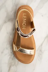 Sandalia de cuero color dorado con tiras marrón y estampado animal print, con plataforma marrón.