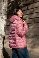 Campera puffer ultraliviana color beige, con diseño acolchado horizontal, capucha incorporada, cierre frontal y bolsillos laterales.