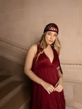 Vestido largo color marrón con bordados florales a tono, escote en V y corte imperio. Tiene falda amplia con volados y breteles finos.