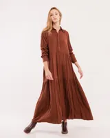 Vestido largo color marrón con cuello camisero, manga larga con puños elásticos y falda escalonada con volados.