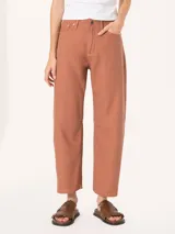 Pantalón de mujer color terracota, estilo slouchy o ancho, con tiro alto y cierre frontal. Presenta detalles de costura o pinzas a la altura de las rodillas.