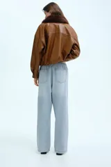 Pantalón de denim celeste de corte holgado, con cintura elástica ajustable con cordón, bolsillos delanteros y traseros, y pierna ancha.