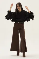 Cardigan de tejido de punto con detalles calados, trenzas y flecos en mangas y espalda. Presenta cierre frontal con botones, cuello redondo y mangas tres cuartos.