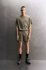 Short deportivo de entrenamiento color marrón, confeccionado en tejido técnico ligero y elástico. Cuenta con cintura elástica ajustable con cordón, bolsillos frontales, bolsillo trasero con cierre y aberturas laterales en el bajo. Incluye detalle de logo estampado en la pernera.