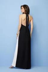 Vestido largo negro y blanco con diseño color block, cuello halter y abertura lateral en la falda.
