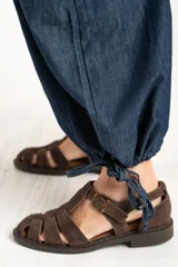 Pantalón tipo jean de corte wide leg y diseño balloon, con cintura elástica y cordones ajustables en los tobillos. Confeccionado en algodón denim de tono azul oscuro.