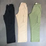 Pantalón cargo de nylon color tostado, corte baggy, con cintura elástica ajustable con cordón y bolsillos laterales con solapa.