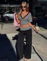 Conjunto compuesto por un top cropped de rayas blancas y negras, con escote en V y mangas cortas, y un pantalón largo negro de pierna ancha con cintura baja y detalle de rayas a juego.