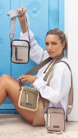 Phone bag color marrón claro con laterales beige, bolsillo frontal con cierre y tirador con flecos. Tiene espacio para celular y billetera, y correa de galón regulable y desmontable.