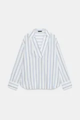 Blusa de manga larga confeccionada en mezcla de viscosa, lino y liocel, con diseño de rayas verticales en tonos celestes y marrones sobre fondo blanco. Presenta cuello solapa con escote en V cruzado.