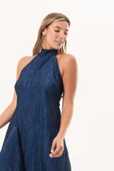 Vestido largo azul de tafeta con textura corrugada, cuello halter, espalda descubierta y falda amplia con tajo lateral y volados.