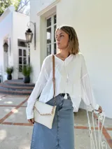 Cartera tipo sobre color crudo, confeccionada en cuero, con correa larga de cuero marrón y costuras decorativas en contraste.