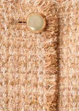 Chaqueta de tweed color tostado con cuello redondo, manga larga, cuatro bolsillos de parche con solapa en la parte delantera y cierre de botones con efecto joya. Presenta terminaciones deshilachadas y forro interior.