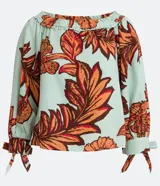 Blusa celeste con estampado de hojas color naranja y marrón, con escote hombro a hombro, mangas 3/4 con lazos en los puños y corte holgado.