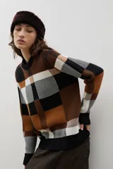 Sweater de punto con diseño jacquard a cuadros en tonos azul, marrón, crema y negro. Presenta cuello redondo, puños y ruedo acanalados, con un corte holgado y cómodo.