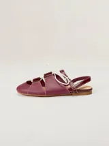 Sandalias planas tipo slingback de cuero marrón, con diseño delantero calado, cierre de cordones y tira trasera ajustable con hebilla.