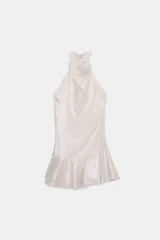 Vestido corto de tela brillante color blanco perla, con cuello halter que se anuda en la parte superior, escote drapeado y bajo con volantes superpuestos.