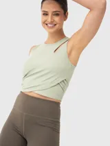 Top crop sin mangas de tejido acanalado en color verde menta. Presenta un diseño cruzado en la parte frontal y una pequeña abertura decorativa en uno de los hombros.