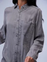 Camisa celeste de tencel marca Hester & Orchand, con cuello con solapa, escote en V, abertura central con botones, bolsillo aplicado y ruedo desflecado.