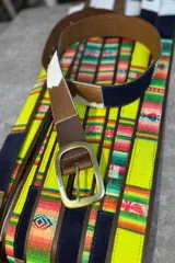 Cinturón de cuero marrón combinado con inserciones de gamuza, pelo vacuno y tejido tipo aguayo de colores. Cuenta con hebilla metálica rectangular envejecida.