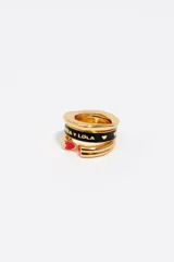 Anillo modular triple de diseño contemporáneo, elaborado en latón con acabado dorado. Presenta una banda central esmaltada en negro con el logo de la marca y corazones, y una banda inferior con detalles de corazones esmaltados en rojo.