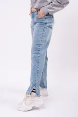 Jean mom fit de tiro alto en color azul claro con lavado vintage. Presenta un corte relajado y tajos laterales en el ruedo de los tobillos.