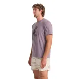Remera lila de manga corta con estampado gráfico frontal en tonos oscuros que incluye una pila de rocas y texto.