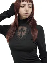 Remera de manga larga negra con cuello alto, confeccionada en viscosa y elastano. Presenta un panel frontal de encaje transparente en el pecho con un aplique de cruz bordada y detalles de cruces en las mangas.