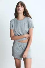 Conjunto de pijama de dos piezas, compuesto por una remera de manga corta y un short, ambos en tela gris jaspeada con estampado de pequeñas flores blancas.