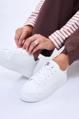 Champion de plataforma color blanco, con cordones al tono y detalle metálico plateado en la lengüeta y el talón.