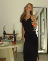 Vestido largo negro de tirantes finos, con escote festoneado y corte al cuerpo con abertura lateral en la falda.