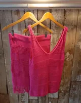 Conjunto de dos piezas de tejido de punto de algodón en color fucsia, compuesto por una musculosa de escote en V y una pollera con flecos en el ruedo.