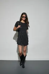 Vestido corto negro con lentejuelas y flecos colgantes, de manga corta y cuello redondo.