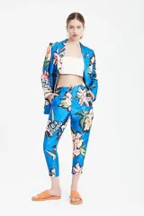 Pantalón sastre azul con estampado de flores y texto en blanco. Tiro alto, corte relajado, cintura pinzada y pierna recta.