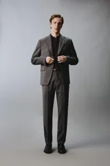Pantalón de traje de corte regular fit, confeccionado en lana de origen italiano. Presenta un diseño a cuadros sutiles, bolsillos delanteros, bolsillos traseros de doble vivo con botón y cierre frontal con cremallera y botón.