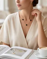 Collar de acero con baño de oro, con cadena eslabonada y tres dijes en forma de trébol u onix negro con borde dorado.
