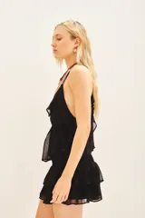 Top negro con escote en V, decorado con volados en el frente y breteles finos dobles. Confeccionado en viscosa georgette, presenta un ajuste elástico en la cintura y forrería a tono.