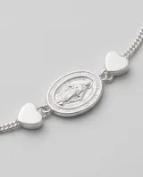 Pulsera de acero con baño de plata, con dije central ovalado de la Virgen Milagrosa y dos pequeños dijes en forma de corazón a los costados.