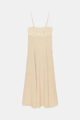 Vestido midi de color beige con escote recto adornado con un panel de encaje semitransparente, tirantes finos ajustables y falda fluida con cierre lateral con cremallera oculta.