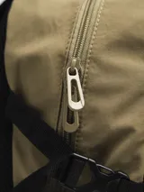 Mochila color arena con detalles en gris y negro. Cuenta con un compartimento principal con cierre, un bolsillo frontal con cordón elástico y bolsillos laterales de malla.