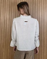 Blusa color lila con estampado vertical de ramas y hojas blancas, cuello alto con volados y escote en V. Presenta mangas largas abullonadas con puños elastizados.