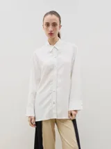 Camisa de corte holgado y diseño clásico, confeccionada en tela satinada con un sutil estampado floral tono sobre tono. Presenta cuello camisero, cierre frontal con botones y mangas largas con puños rectos.