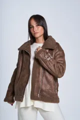 Campera gamulán marrón de símil cuero, con interior de corderoy al tono, cierre frontal con cremallera y cuello con solapas grandes. Presenta detalles de hebillas en los puños y bolsillos laterales con cierre.