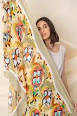 Pañuelo de forma cuadrada con estampado artístico de flores abstractas en tonos naranja, turquesa y negro sobre fondo color visón. Presenta bordes con terminación desflecada.