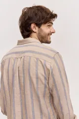 Camisa de manga larga de lino con diseño a rayas en tonos celestes y blancos, cuello camisero clásico y cierre frontal de botones.