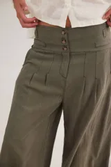 Pantalón de tiro alto en color azul, con cierre frontal de tres botones, pinzas en la cintura y corte holgado.