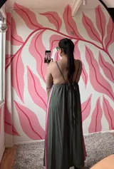 Vestido largo verde oliva con breteles finos y corte evasé. Presenta un panel lateral en color rosa.