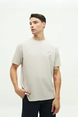 Remera de manga corta color beige, con textura de waffle y logo circular estampado en el pecho.