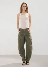 Pantalón cargo de jean color verde militar, de tiro medio, corte ancho y bolsillos laterales con solapa.
