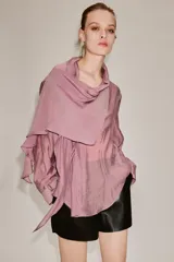 Camisa de manga larga confeccionada en mezcla de lyocell, con cuello fluido tipo pañuelo integrado, cierre frontal con botones ocultos por solapa y bajo redondeado asimétrico.